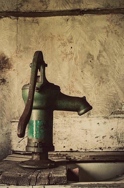 An antique hand water pump and sink inside a very old farm house.